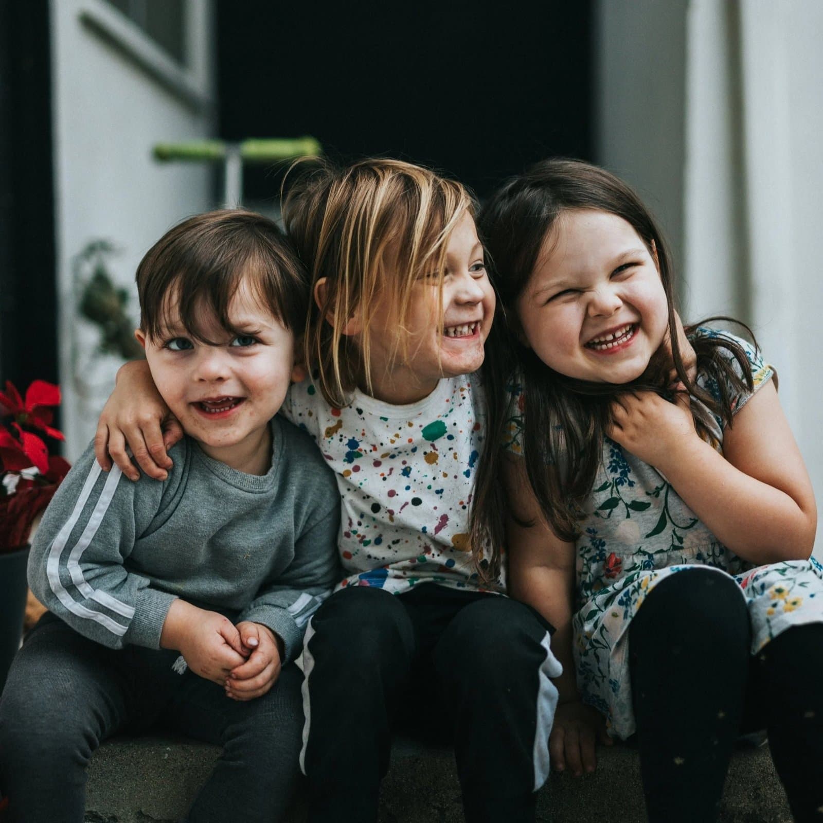 Three happy children sitting together and smiling.
